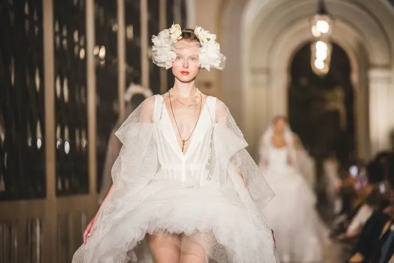 عارضة أزياء ترتدي فستان زفاف مبتكر من تصميم فيفيان ويستوود، مع زينة رأس من الزهور، أثناء عرض أزياء في برشلونة.