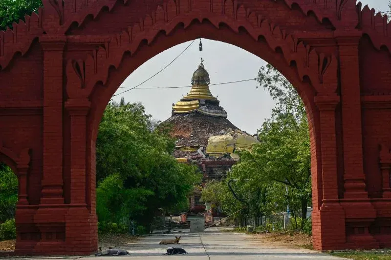 دمار واضح في معبد بوذي في ماندالاي بعد الزلزال المدمر، مع وجود حطام وأشجار حوله، مما يعكس آثار الكارثة في المدينة.