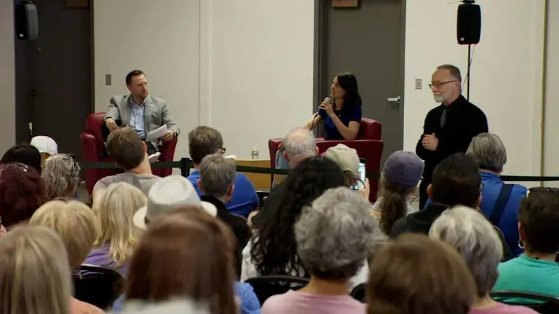 جلسة حوارية في قاعة بلدية حيث تتحدث النائبة ماري جلوسينكامب بيريز مع الحضور، وسط تفاعل حماسي من الجمهور.