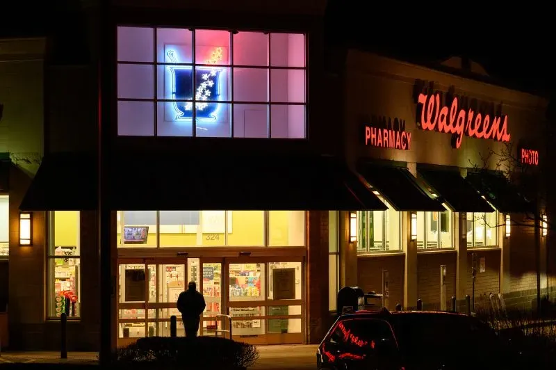واجهة متجر Walgreens تظهر بأضواء ملونة مع شخص واقف في المدخل، مشيرة إلى القلق بشأن السرقة وتأثير ذلك على تجربة التسوق.