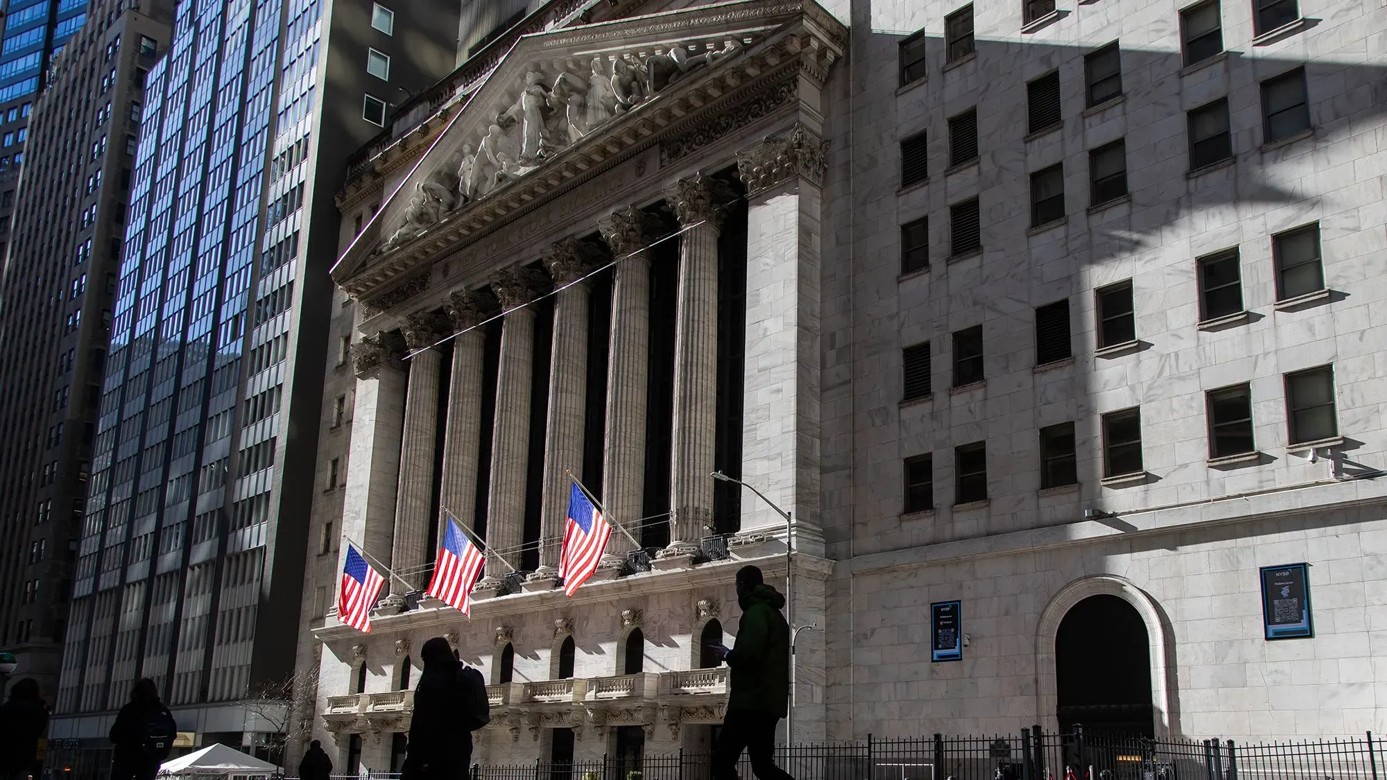 واجهة بورصة نيويورك مع أعلام أمريكية، تعكس النشاط المالي القوي وتزايد المكافآت في وول ستريت لعام 2024.