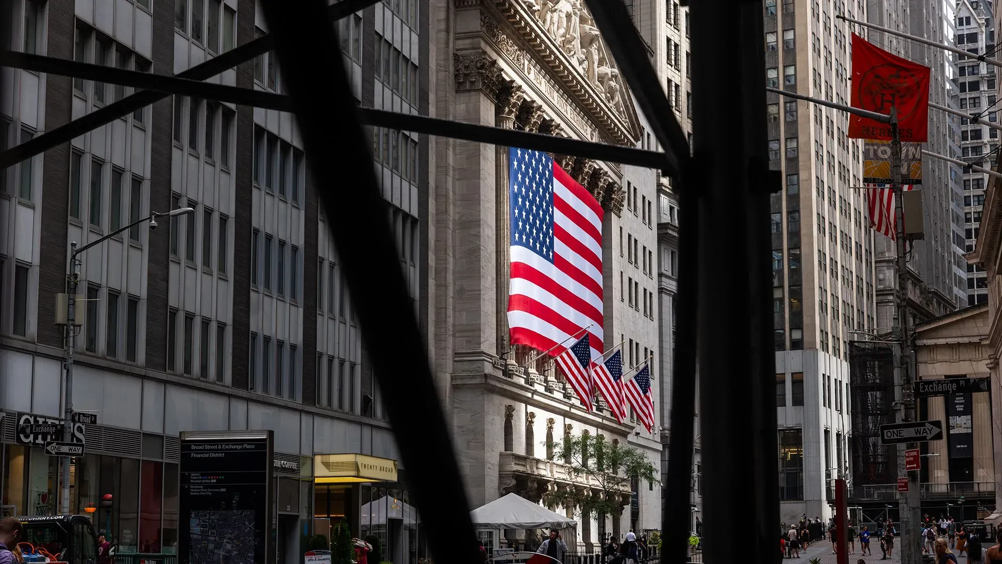 واجهة بورصة نيويورك مع علم الولايات المتحدة، تعكس أجواء الأسواق المالية وسط التوترات التجارية التي يثيرها ترامب.