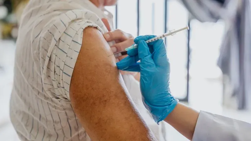 تظهر الصورة شخصًا يتلقى لقاح الهربس النطاقي في ذراعه، مما يعكس أهمية التطعيم للوقاية من المرض وتقليل خطر الإصابة بالخرف.