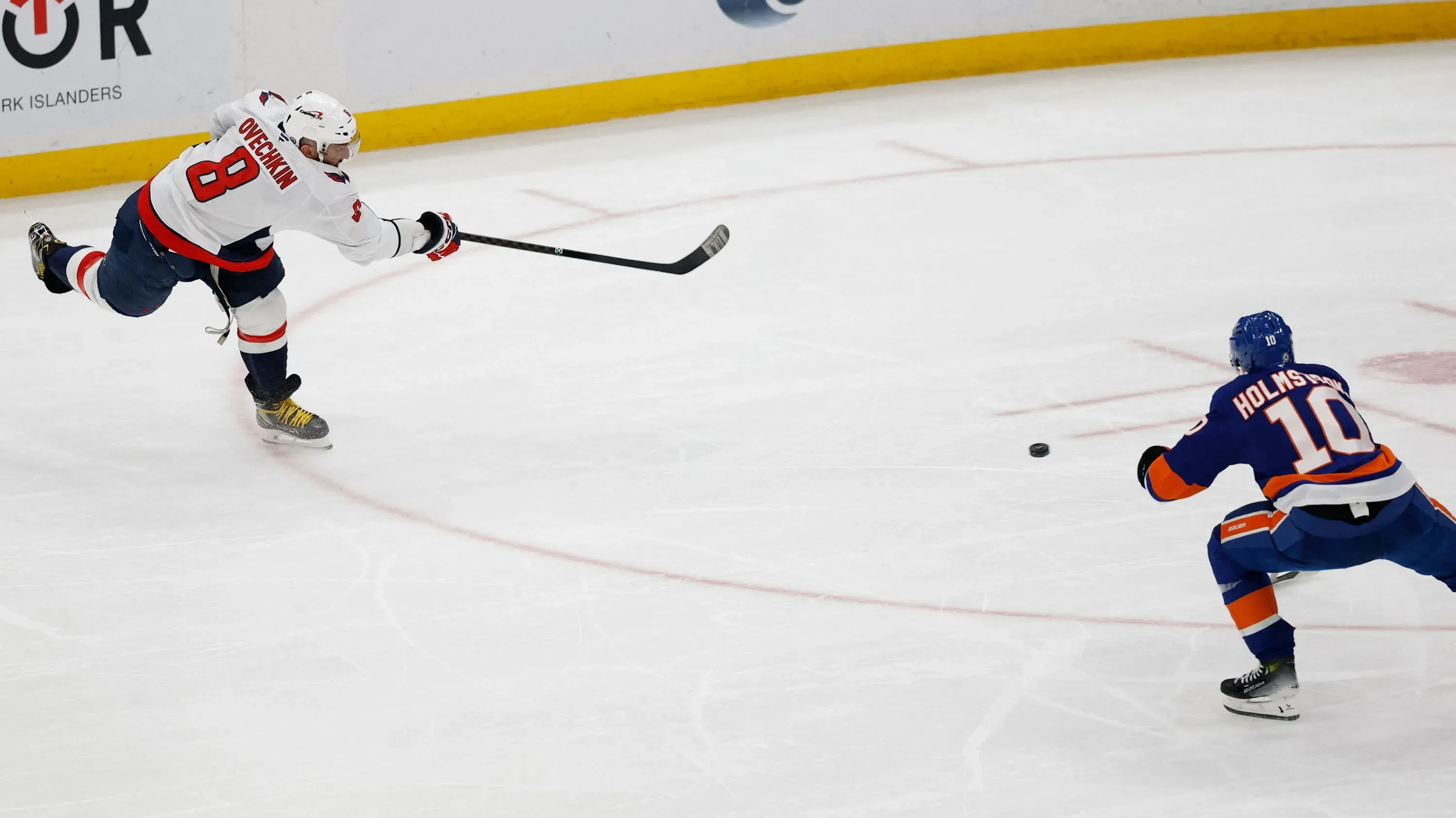 ألكسندر أوفيتشكين، لاعب واشنطن كابيتالز، يسدد الكرة في مباراة هوكي، مع لاعب منافس يتجه نحوها، وسط أجواء حماسية.