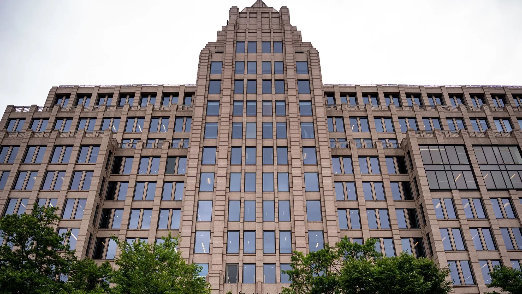 مبنى صحيفة واشنطن بوست يظهر من الأسفل، مع نوافذ كبيرة وأشجار في المقدمة، مما يعكس التوترات الداخلية بعد إعلان جيف بيزوس عن تغييرات تحريرية.