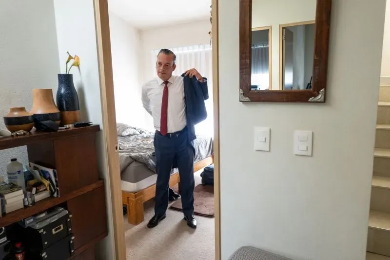 محامٍ يرتدي سترة رسمية ويستعد للخروج، مع نظرة جادة تعكس التوتر في السياسة المكسيكية وسط ارتفاع العنف.