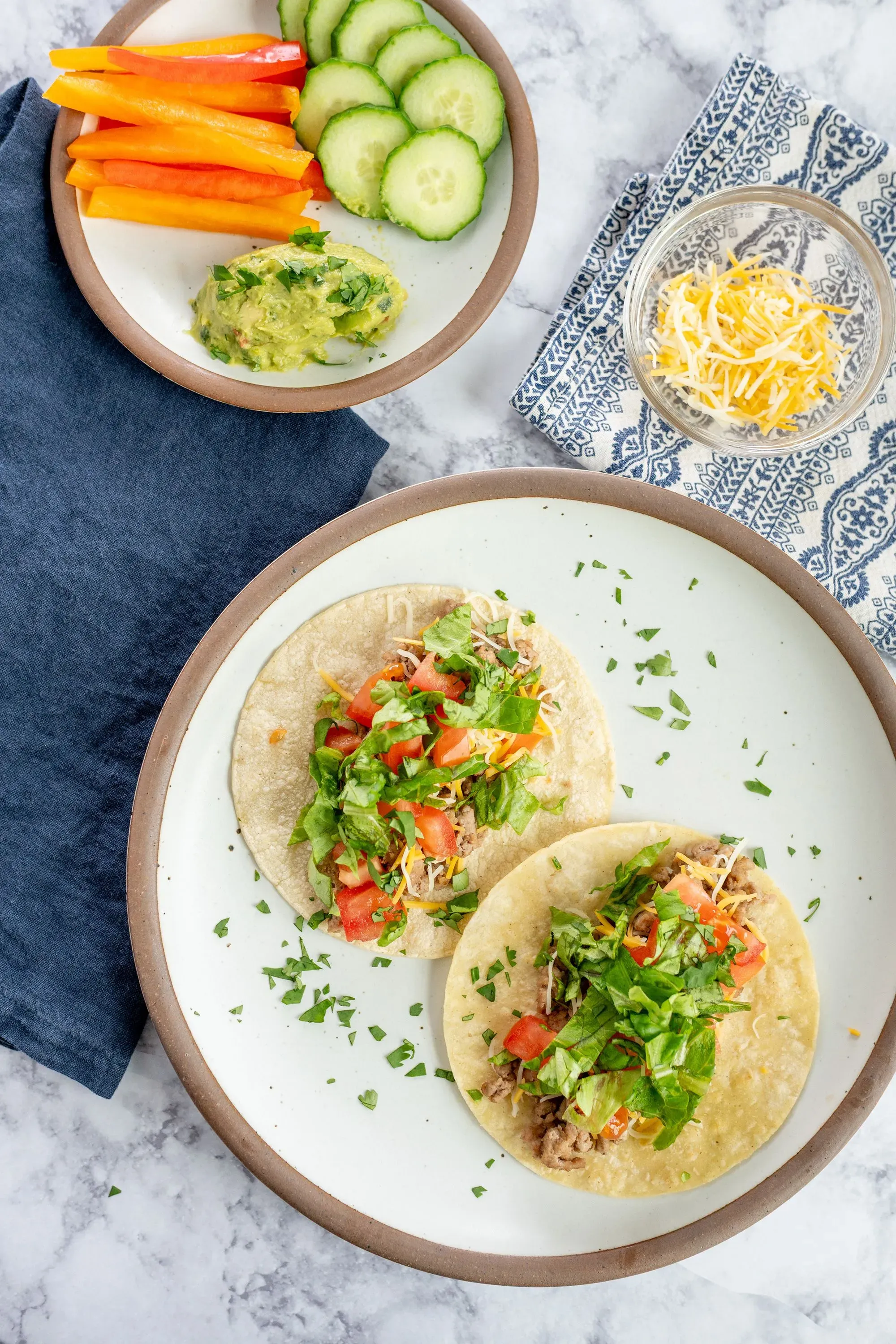 طبق يحتوي على تورتيا محشوة باللحم والخضروات، مع طبق جانبي من الخضروات المقطعة والحم guacamole، مما يعكس توجيهات الحمية الغذائية المتنوعة.