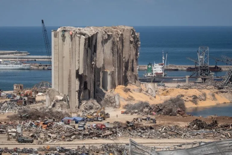 بقايا صوامع مرفأ بيروت مدمرة جزئياً وسط أنقاض الانفجار الذي وقع في أغسطس 2020، مع رؤية البحر في الخلفية.