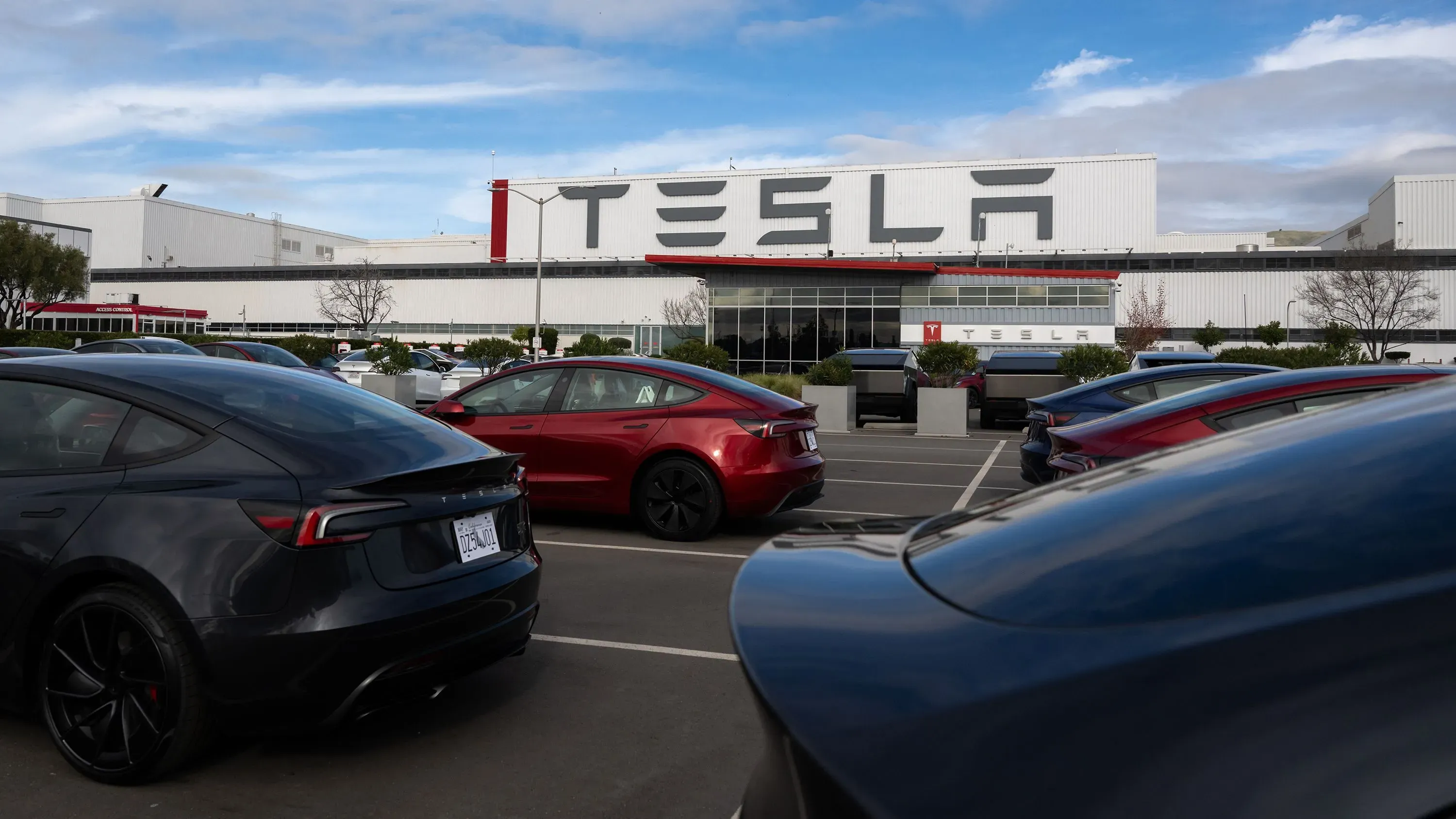 موقع مصنع تسلا في فريمونت، كاليفورنيا، مع سيارات كهربائية متوقفة في الموقف، يعكس القضايا المتعلقة بالتمييز العنصري في الشركة.