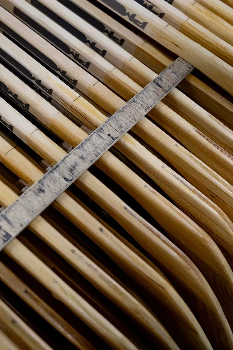 عصا هوكي خشبية مكدسة مع مسطرة قياس، تعكس التحديات التي تواجه صناعة الهوكي في كندا بسبب الرسوم الجمركية الأمريكية.