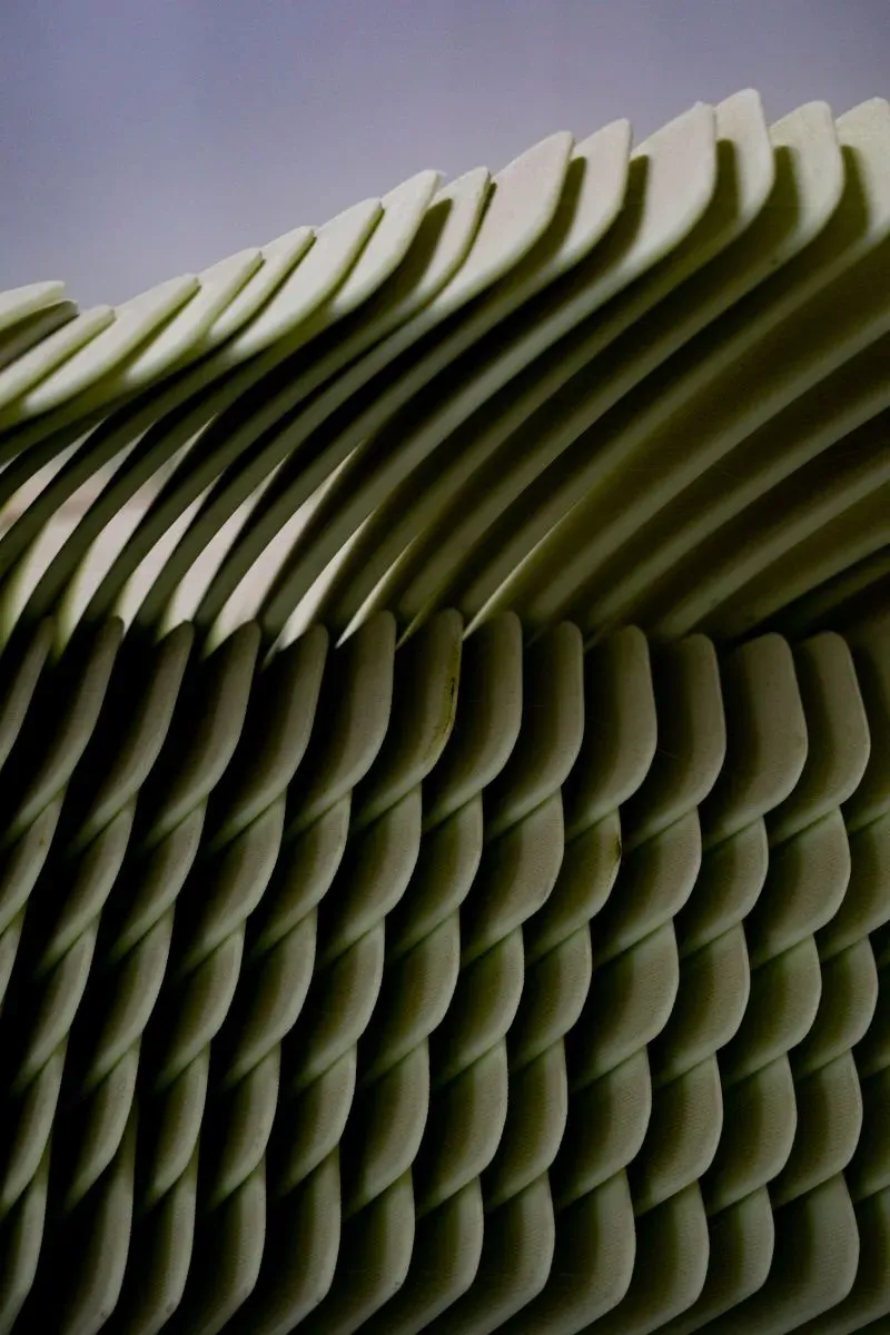 صورة تظهر مجموعة من الألواح المنحنية بلون أخضر فاتح، تعكس تصميمًا فنيًا يعبر عن الحركة والتداخل، مما يعكس موضوع الابتكار في صناعة الهوكي.