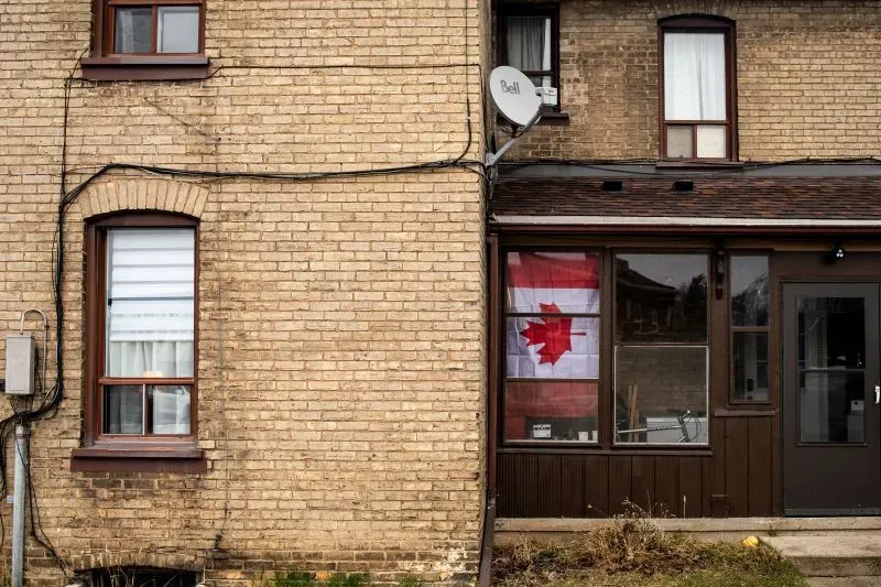 علم كندا يتدلى من نافذة مبنى قديم في برانتفورد، أونتاريو، مما يعكس مشاعر الفخر والقلق في ظل الحرب التجارية الحالية.