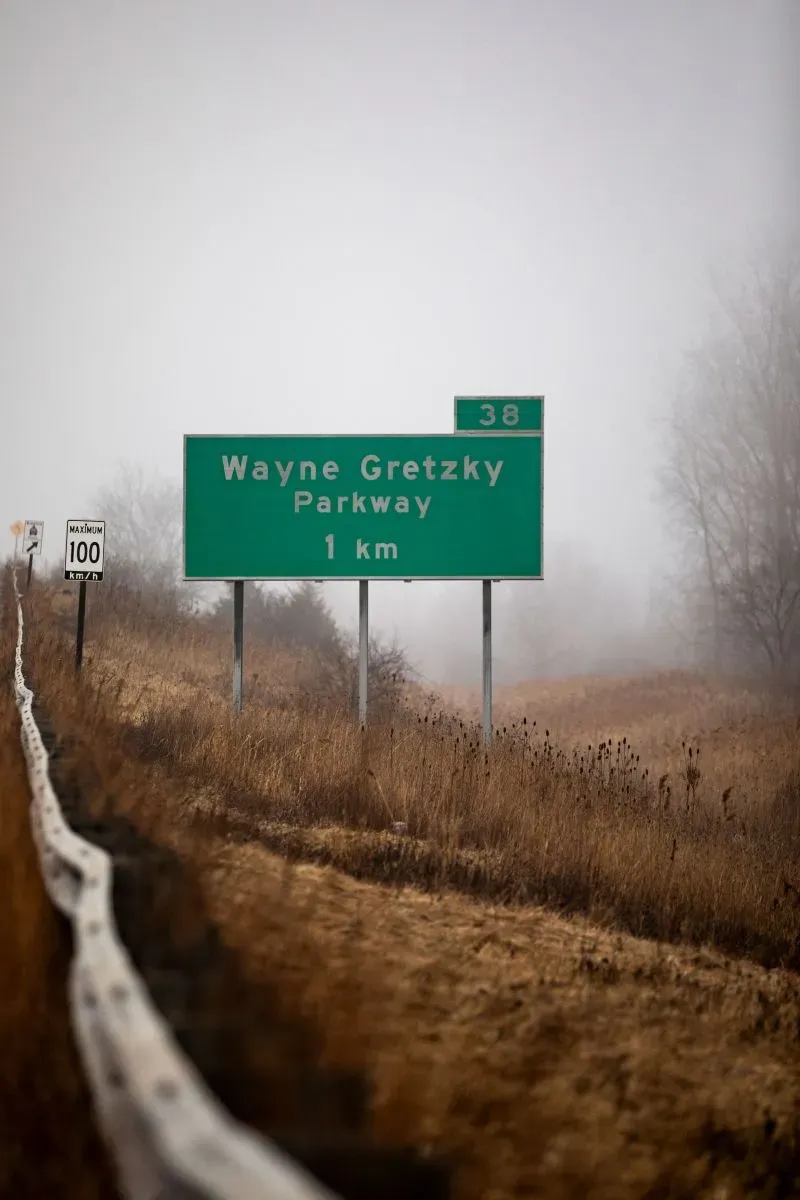 لافتة تشير إلى طريق واين جريتسكي، محاطة بالضباب والأراضي الجافة، تعكس تأثيرات الحرب التجارية على الهوكي الكندي.