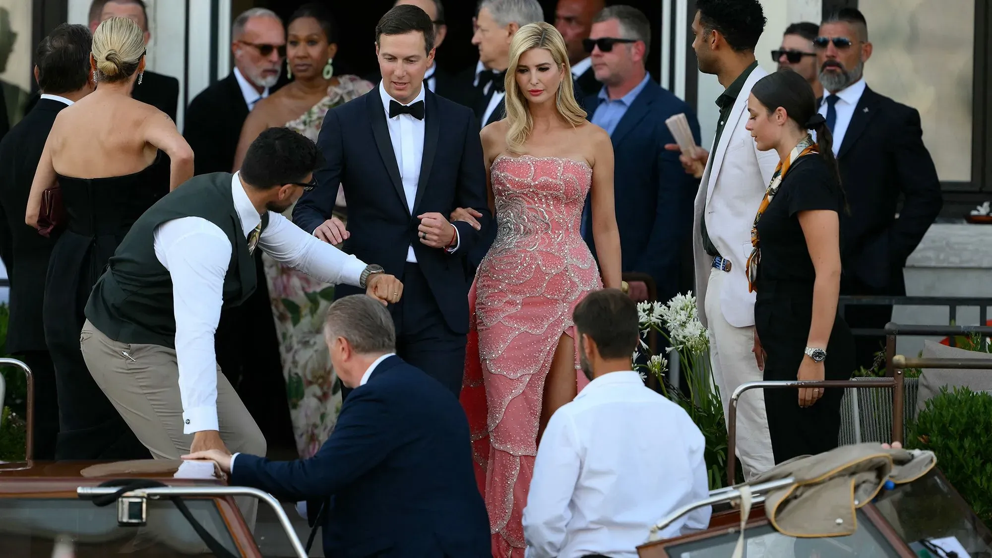 حضور حفل زفاف جيف بيزوس ولورين سانشيز في البندقية، مع ضيوف يرتدون ملابس أنيقة، وتفاصيل احتفالية في الخلفية.