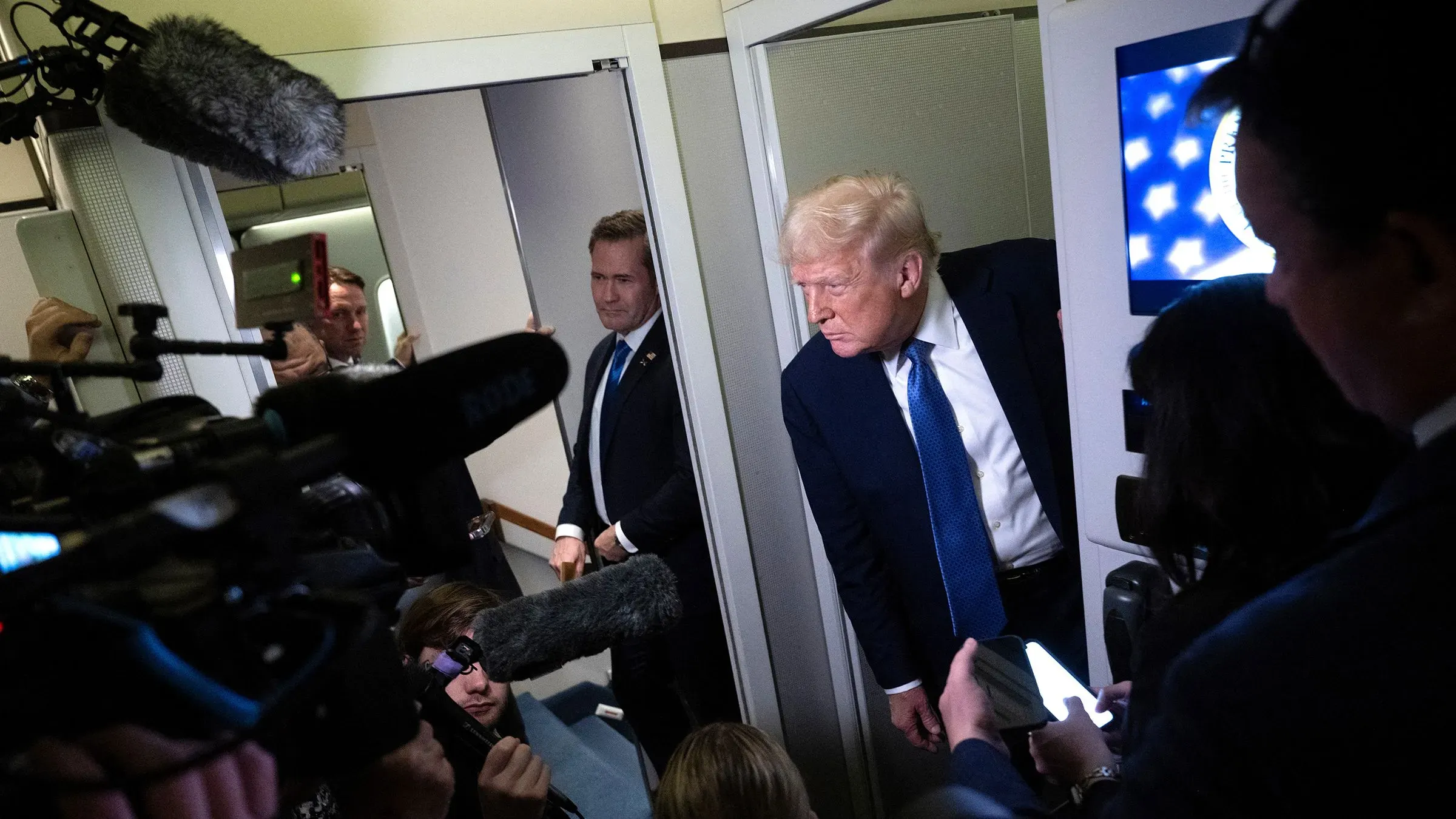 دونالد ترامب يتحدث مع الصحفيين في طائرة، محاطًا بكاميرات وصحفيين، في سياق الجدل حول الترحيل والأزمة الدستورية.