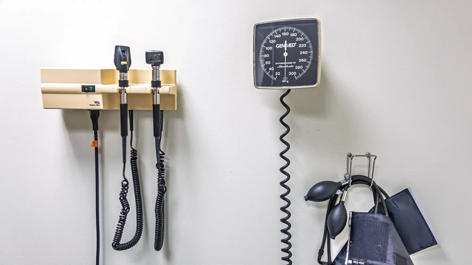 أدوات طبية مثبتة على الحائط تشمل جهاز قياس ضغط الدم ومصباح فحص، تعكس أهمية الرعاية الصحية وبرنامج Medicaid للأمريكيين ذوي الدخل المنخفض.