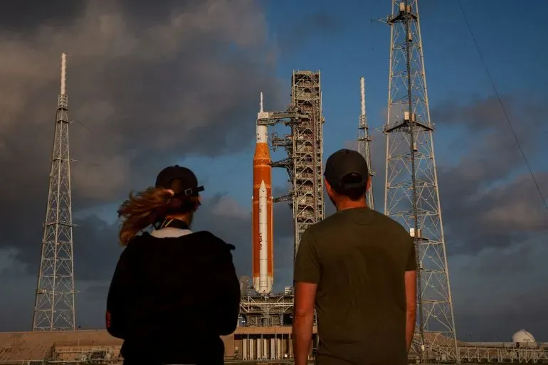 مركبة أرتميس 2 جاهزة للإطلاق من مركز كينيدي للفضاء، حيث يراقب شخصان الإعدادات النهائية قبل المهمة القمرية المأهولة.