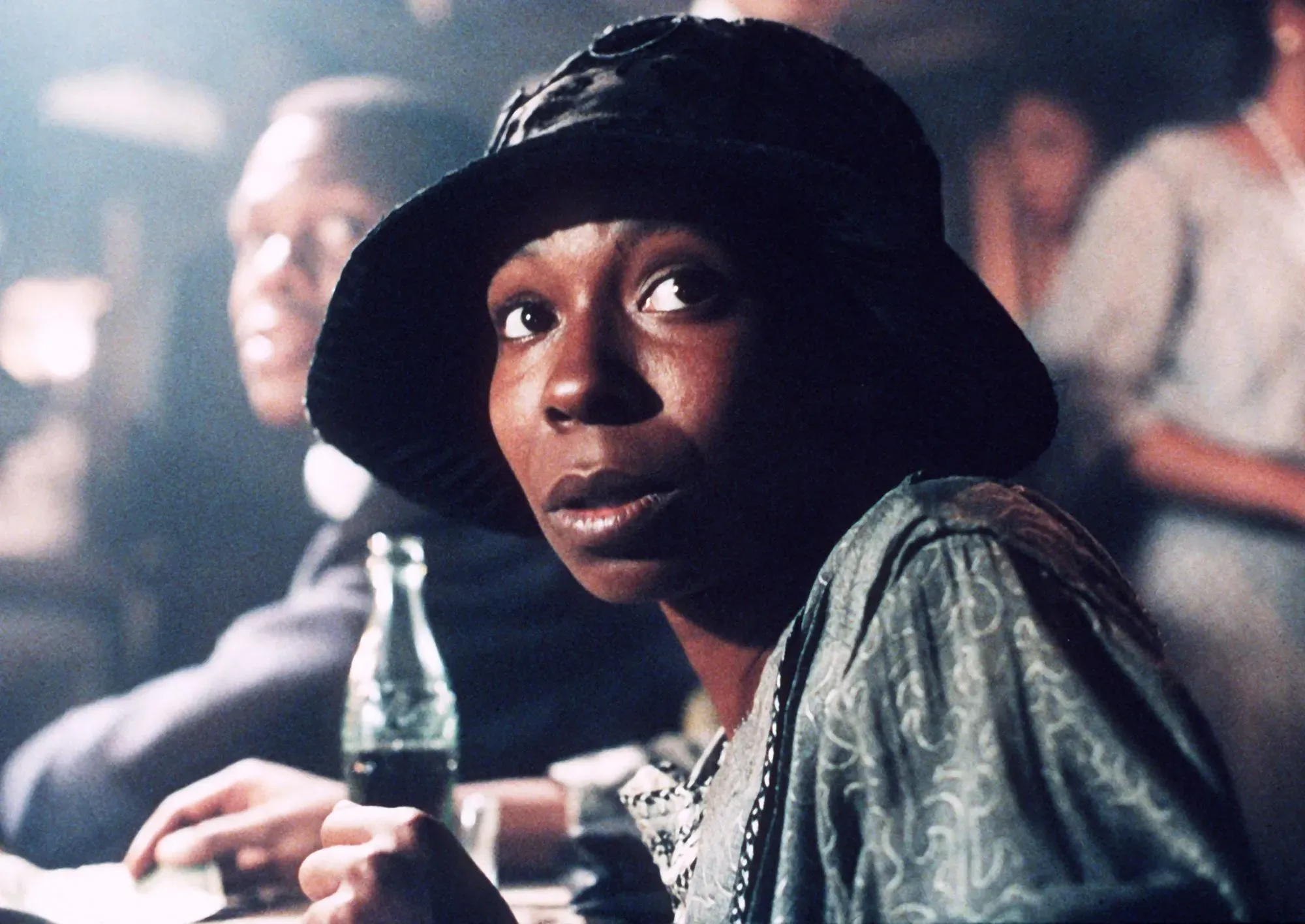 امرأة ترتدي قبعة سوداء تنظر بقلق في مشهد درامي من فيلم، مع وجود شخص آخر في الخلفية. تعكس الصورة أجواء التوتر والتاريخ السينمائي.