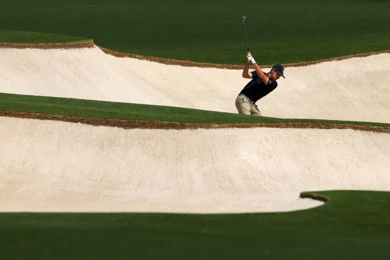 لاعب جولف شاب يتدرب في ملعب أوجوستا الوطني، محاطًا بالرمال والحدائق الخضراء، استعدادًا لبطولة الماسترز.