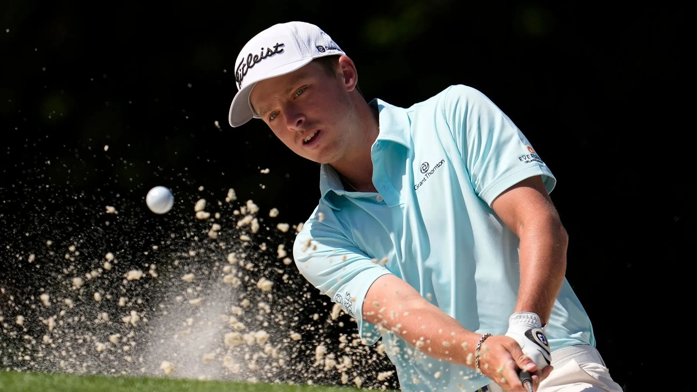 جاستن هاستينغز، لاعب جولف شاب، يضرب الكرة من الرمال في بطولة الماسترز، مع التركيز على أدائه في المنافسة الكبرى.