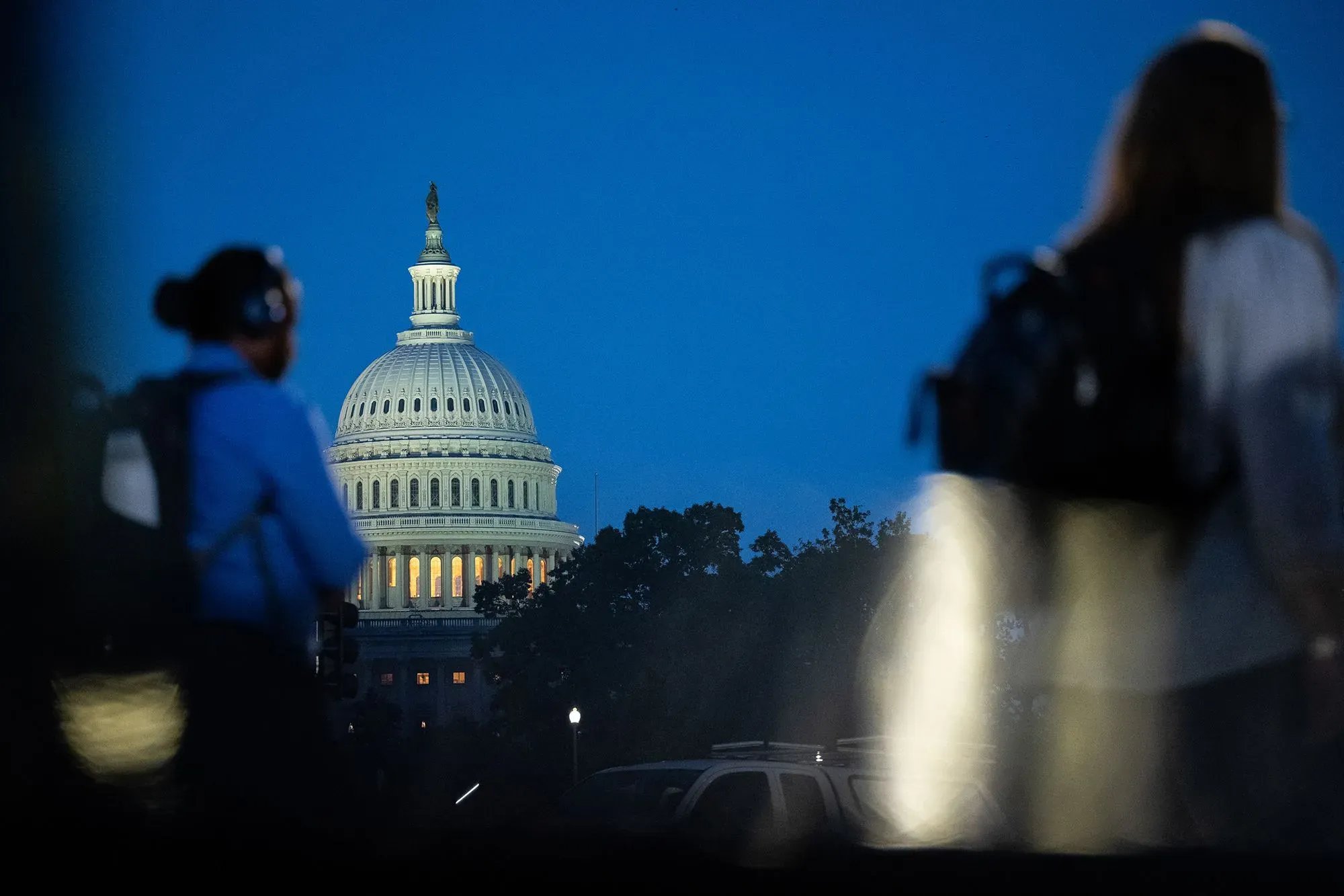 مشهد ليل يظهر مبنى الكابيتول الأمريكي مع أشخاص يسيرون في المقدمة، مما يعكس تأثير الإغلاق الحكومي على الحياة اليومية.