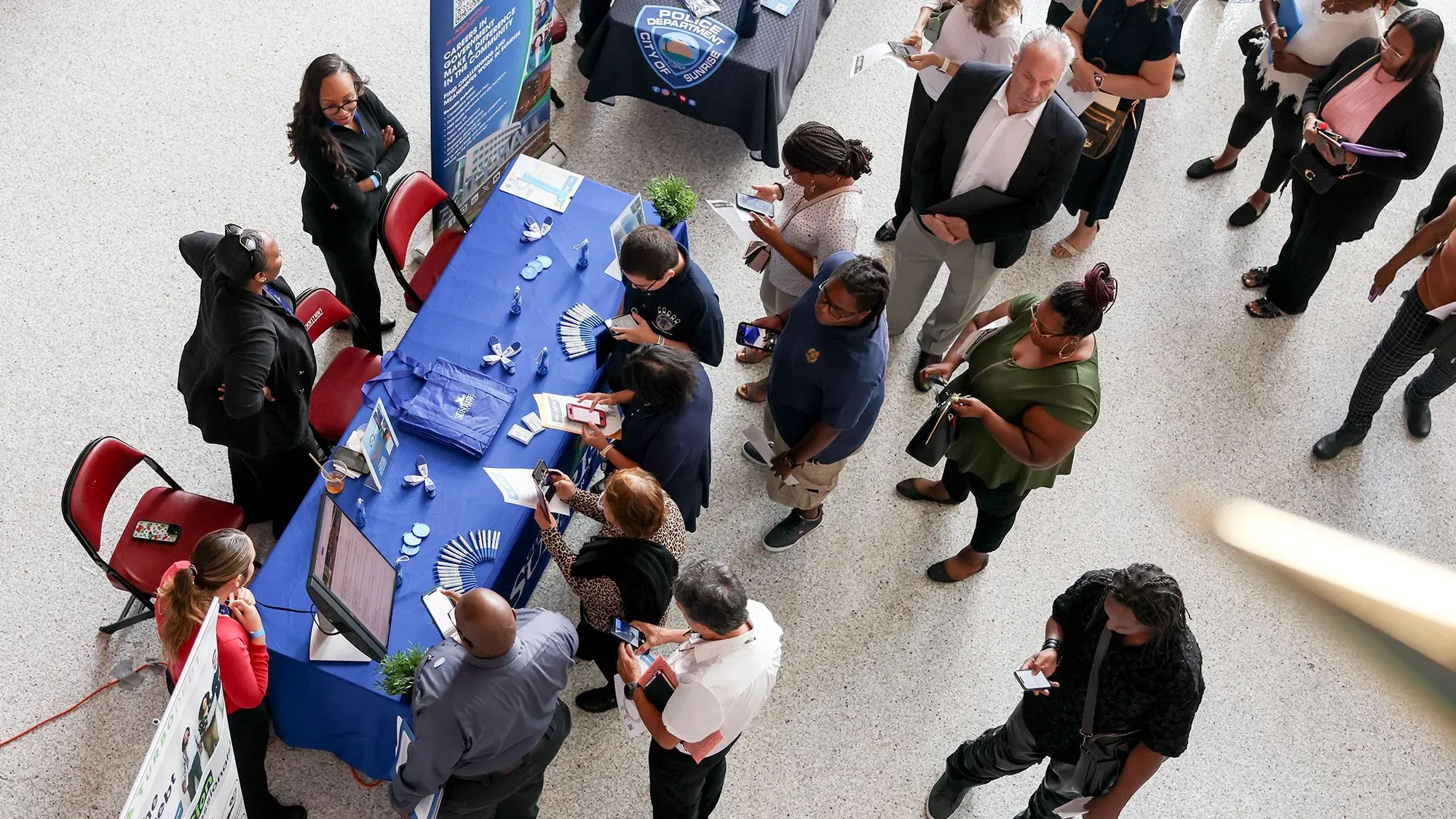 مشاركون في معرض توظيف، حيث يتجمع الباحثون عن عمل حول طاولة تعرض فرص العمل والمعلومات المتعلقة بسوق العمل.