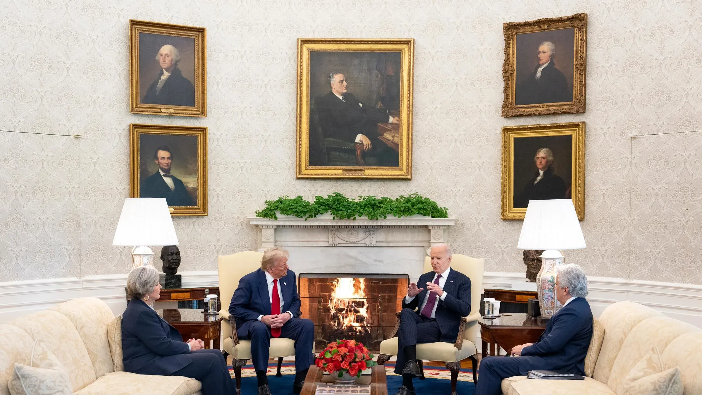 اجتماع بين ترامب وبايدن في المكتب البيضاوي، حيث يجلسان بالقرب من المدفأة، مع لوحات رويستار عن الرؤساء السابقين على الجدران.