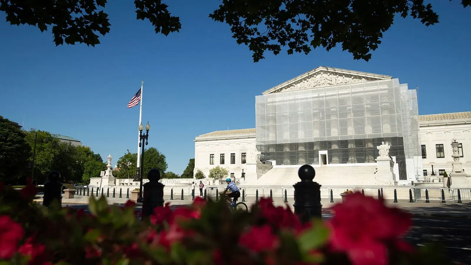 مبنى المحكمة العليا الأمريكية محاط بشبكة حماية، مع وجود العلم الأمريكي يرفرف في الخلفية، مما يعكس النقاشات القانونية حول حق المواطنة بالميلاد.