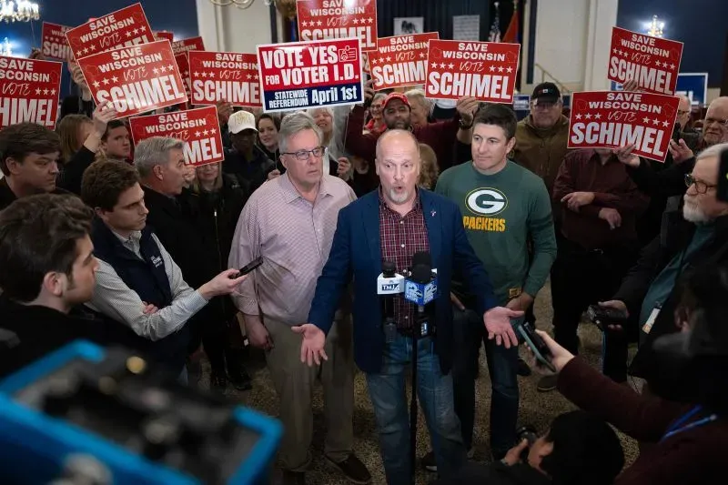 مؤيدو المرشح براد شيميل يتجمعون في حدث انتخابي في ويسكونسن، حاملين لافتات تدعو للتصويت له، بينما يتحدث أحد المتحدثين إلى الحضور.