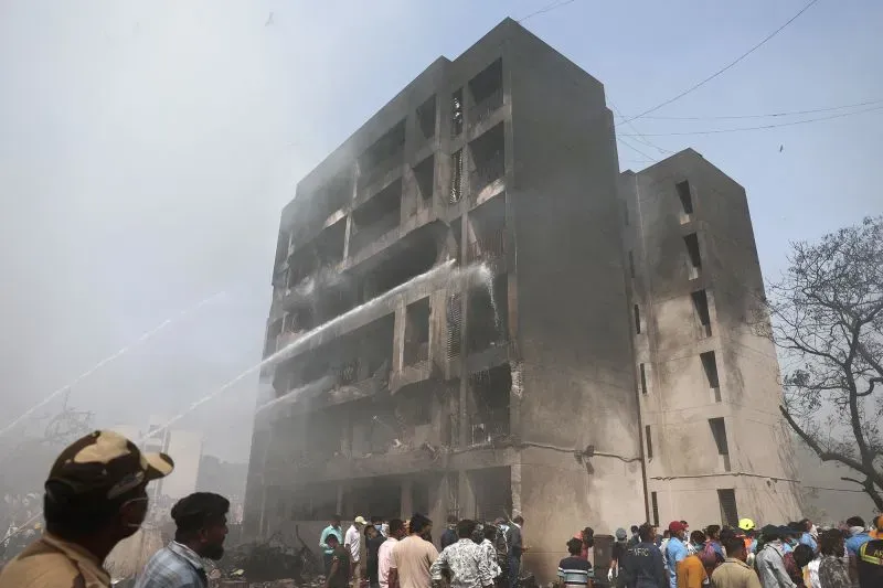 موقع تحطم طائرة بوينج 787-8 دريملاينر في غوجارات، مع رجال الإطفاء يعملون على إخماد النيران وسط حطام المبنى المتضرر.