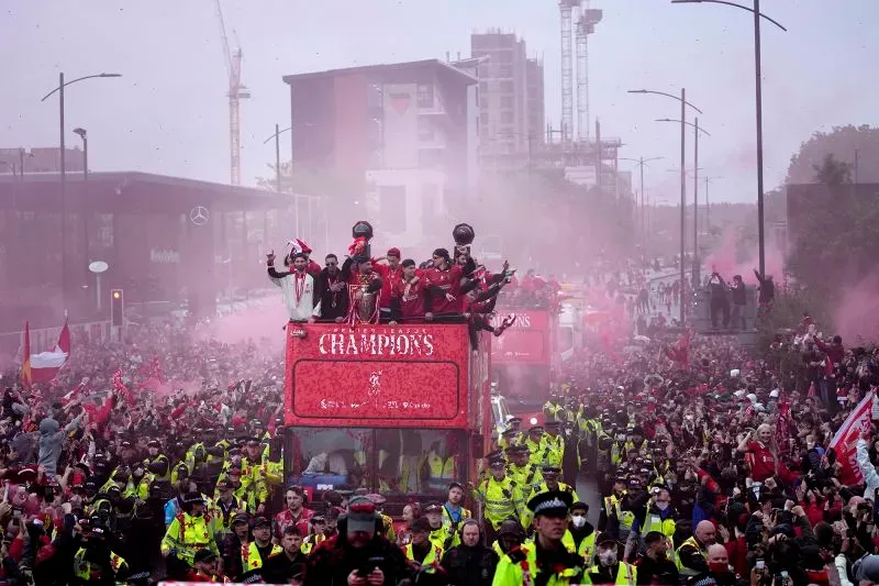 احتفال جماهيري في شوارع ليفربول بمناسبة فوز فريق كرة القدم باللقب، مع حشود كبيرة وأجواء من الفرح، بينما تظهر الشرطة في الخلفية.
