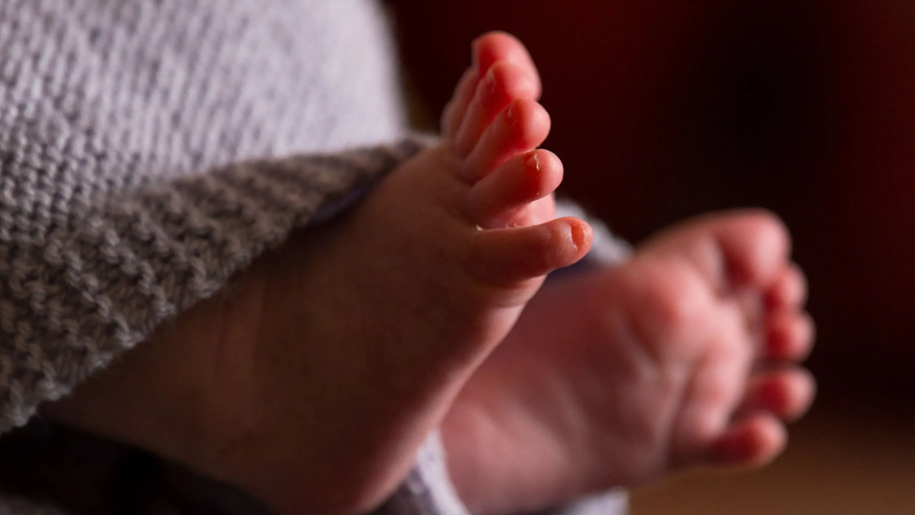 أقدام طفل حديث الولادة مغطاة ببطانية، تعكس القلق حول انخفاض معدل المواليد في الولايات المتحدة واقتراح مكافأة الطفل بقيمة 5000 دولار.