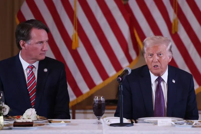 اجتماع يتضمن دونالد ترامب وحاكم ولاية فرجينيا، مع خلفية من الأعلام الأمريكية، يناقشان قضايا التمويل الفيدرالي.