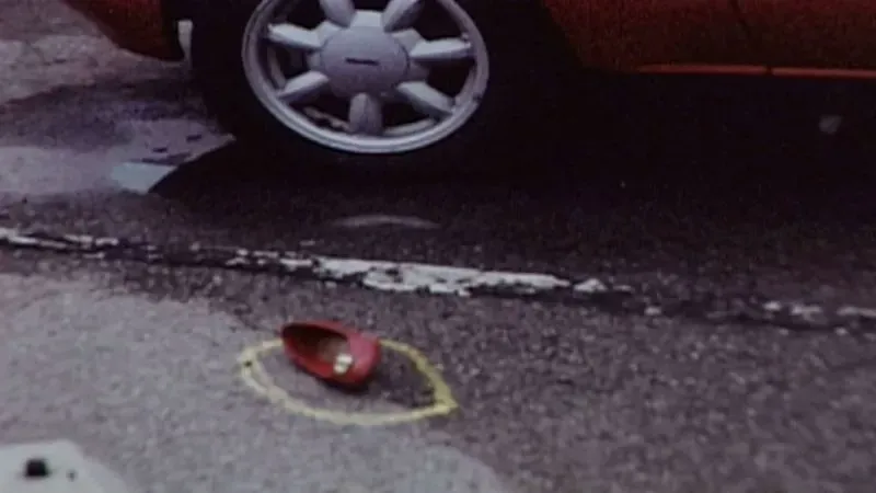 حذاء أحمر متروك على الأرض بجوار سيارة، مع دائرة صفراء حوله، مما يشير إلى موقع حادث اختفاء جودي هويسنترويت في ماسون سيتي.