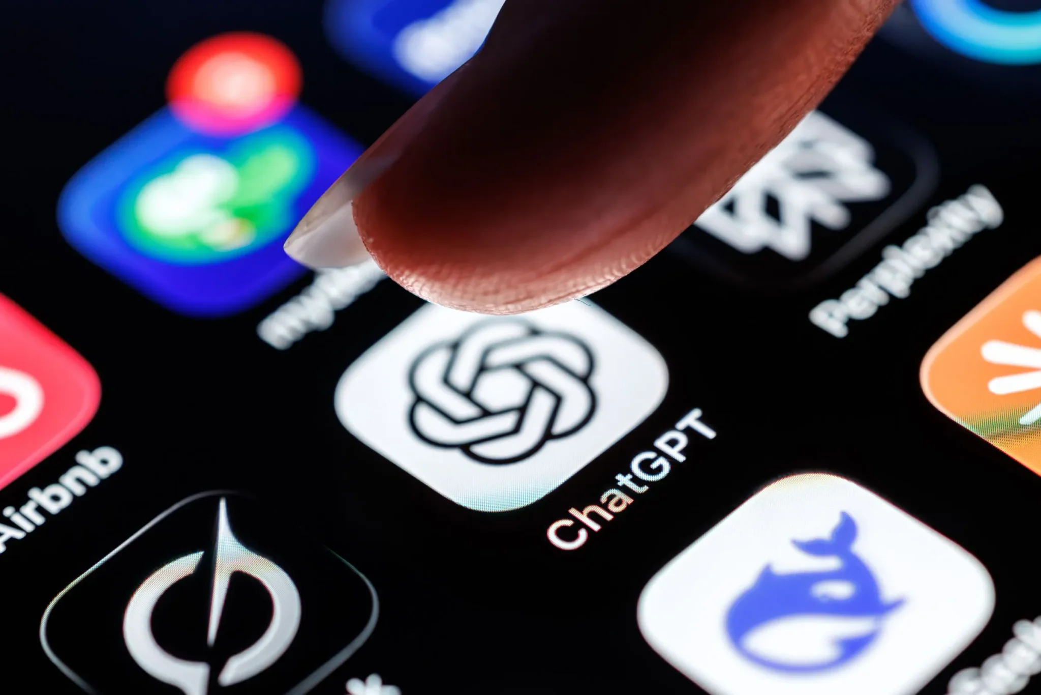 إصبع يضغط على أيقونة تطبيق ChatGPT على شاشة هاتف ذكي، مما يعكس الاهتمام المتزايد بتقنيات الذكاء الاصطناعي.