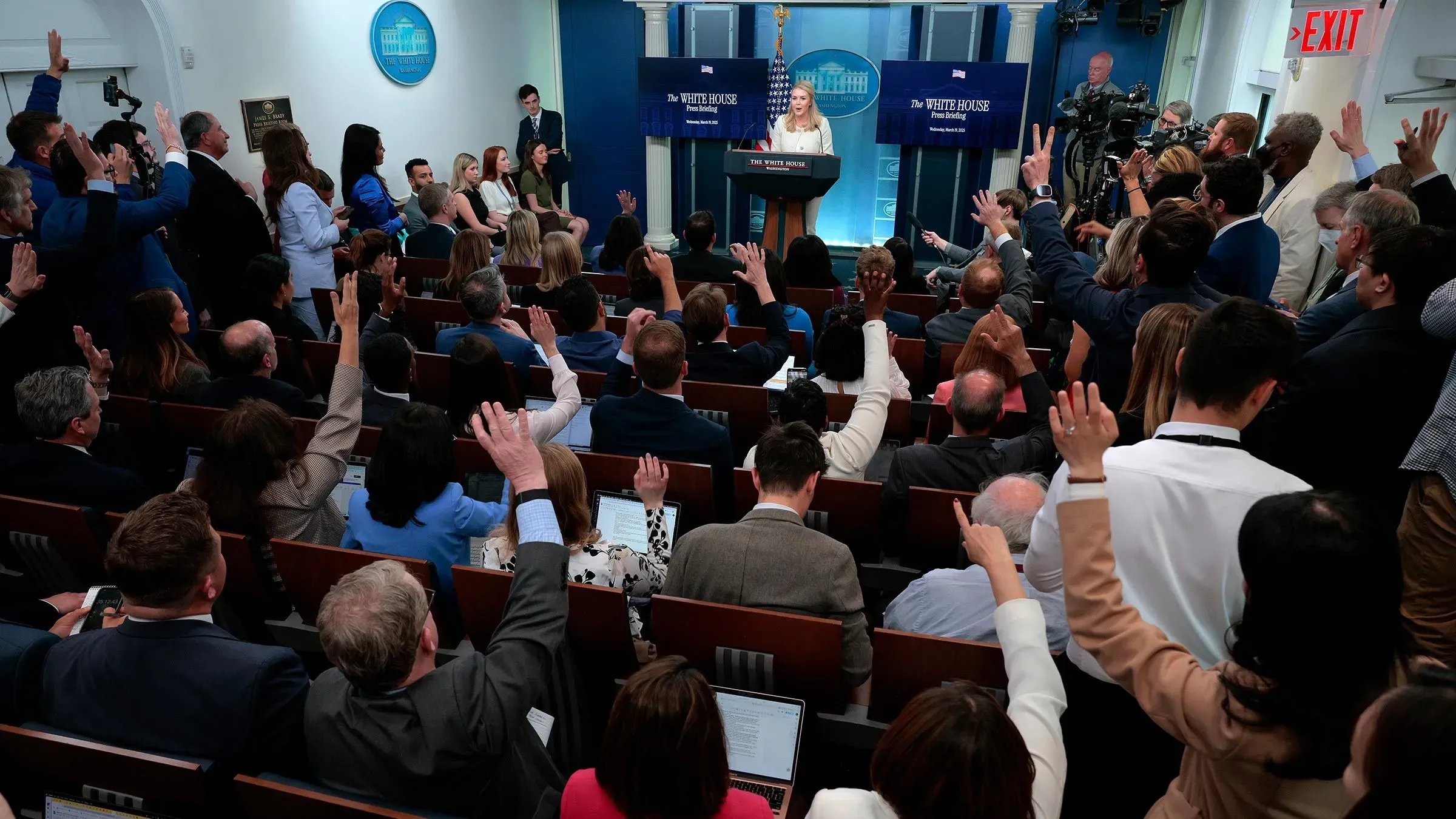 صحفيون يرفعون أيديهم في غرفة الإحاطة الصحفية بالبيت الأبيض، حيث تتحدث السكرتيرة الصحفية كارولين ليفيت عن التغطية الإعلامية.