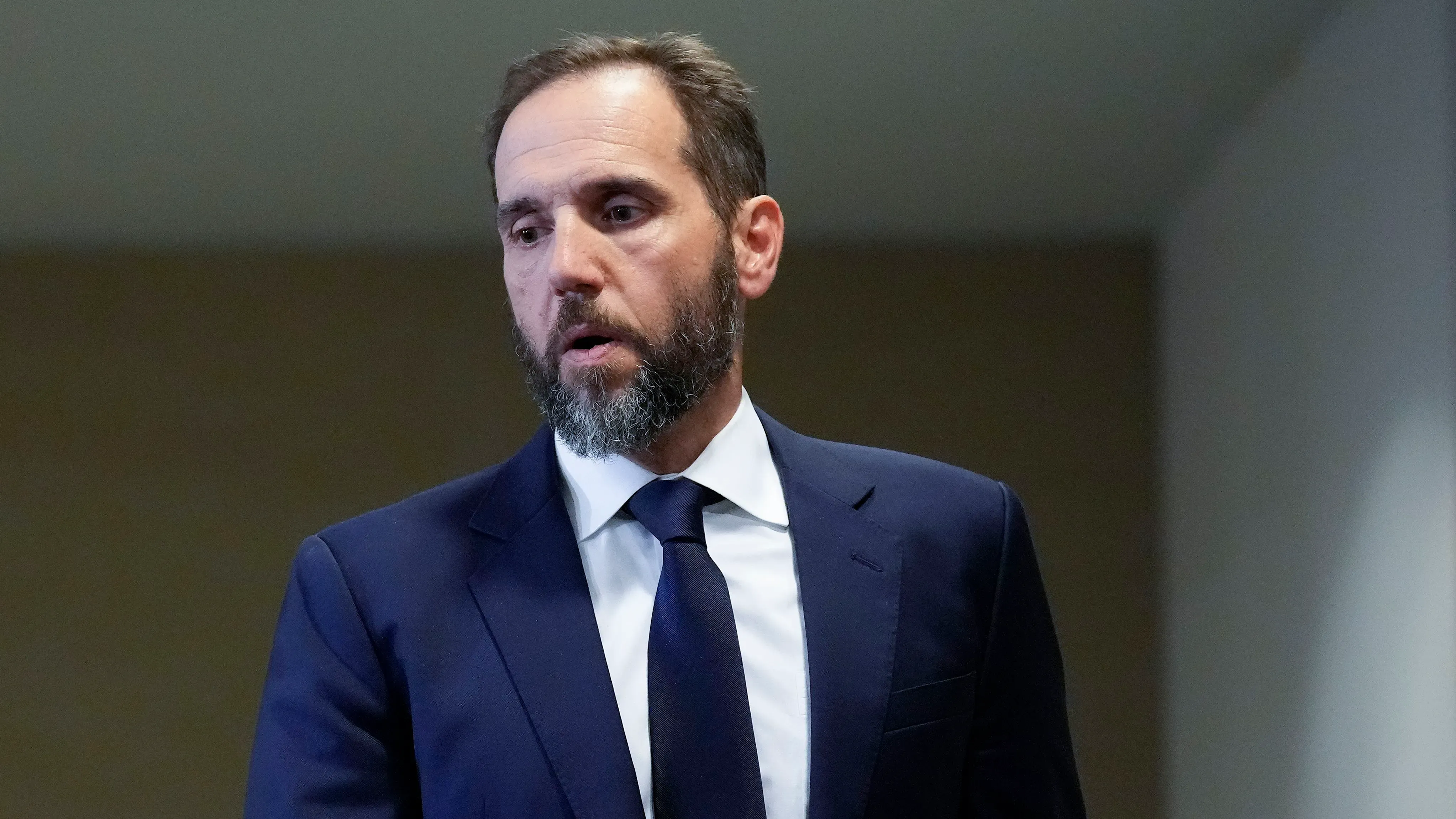 جاك سميث، المستشار الخاص السابق، يتحدث بجدية، مرتديًا بدلة رسمية، في سياق تعليق البيت الأبيض لتصاريح محامي "كوفينغتون آند بيرلنغ".