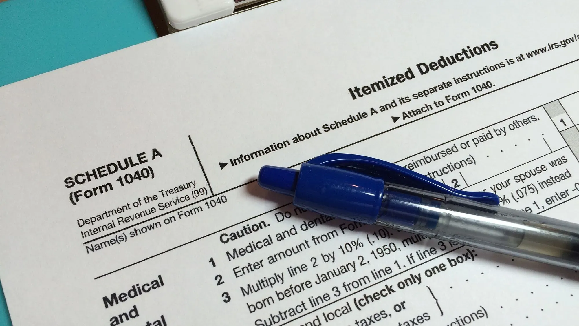 نموذج ضريبي يحمل عنوان "الخصومات المفصلة" مع قلم أزرق، يوضح تفاصيل الخصومات الضريبية الفيدرالية.