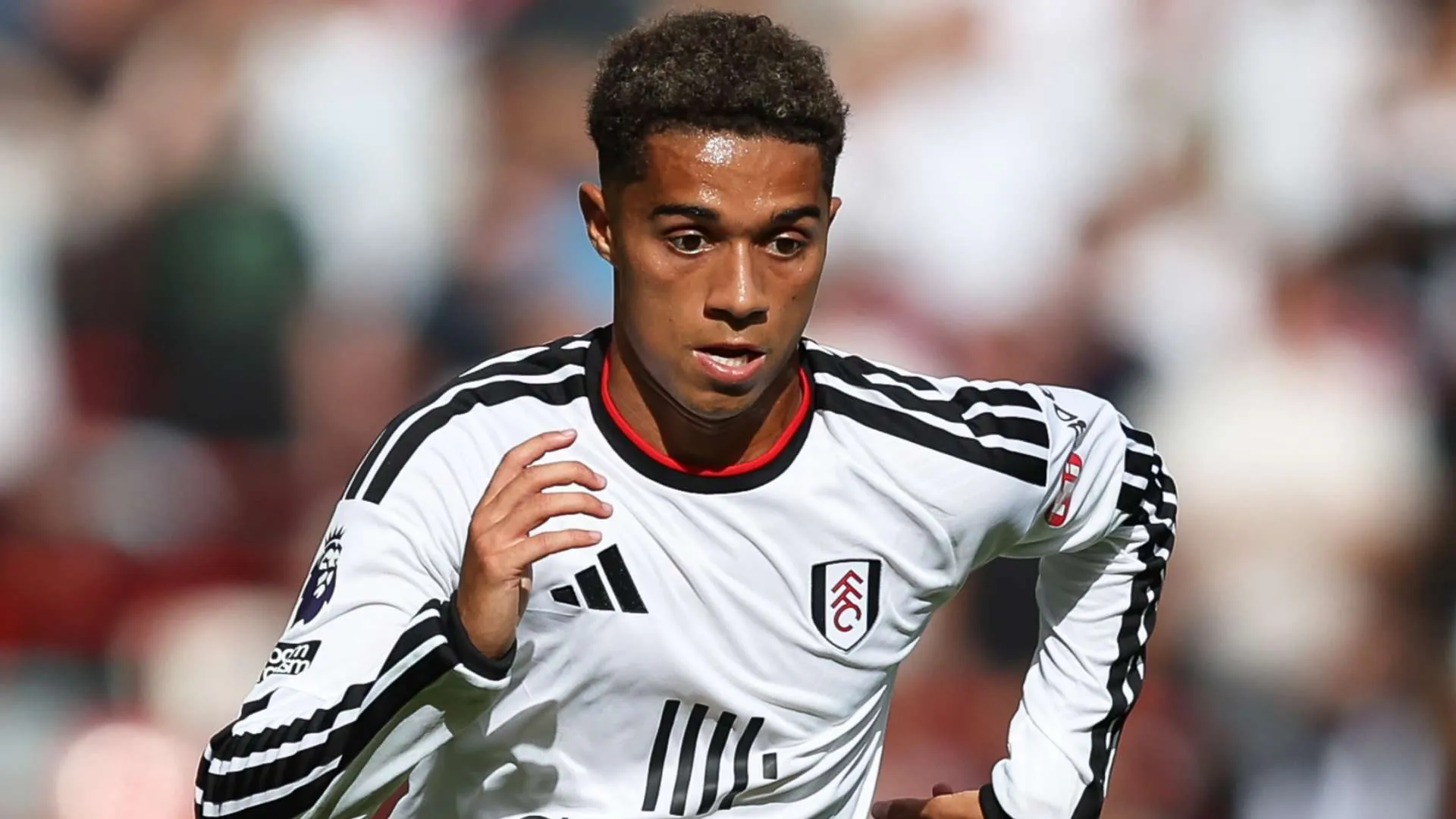 لاعب كرة قدم شاب من أكاديمية Fulham يرتدي زي الفريق الأبيض أثناء مباراة في الدوري الإنجليزي الممتاز.