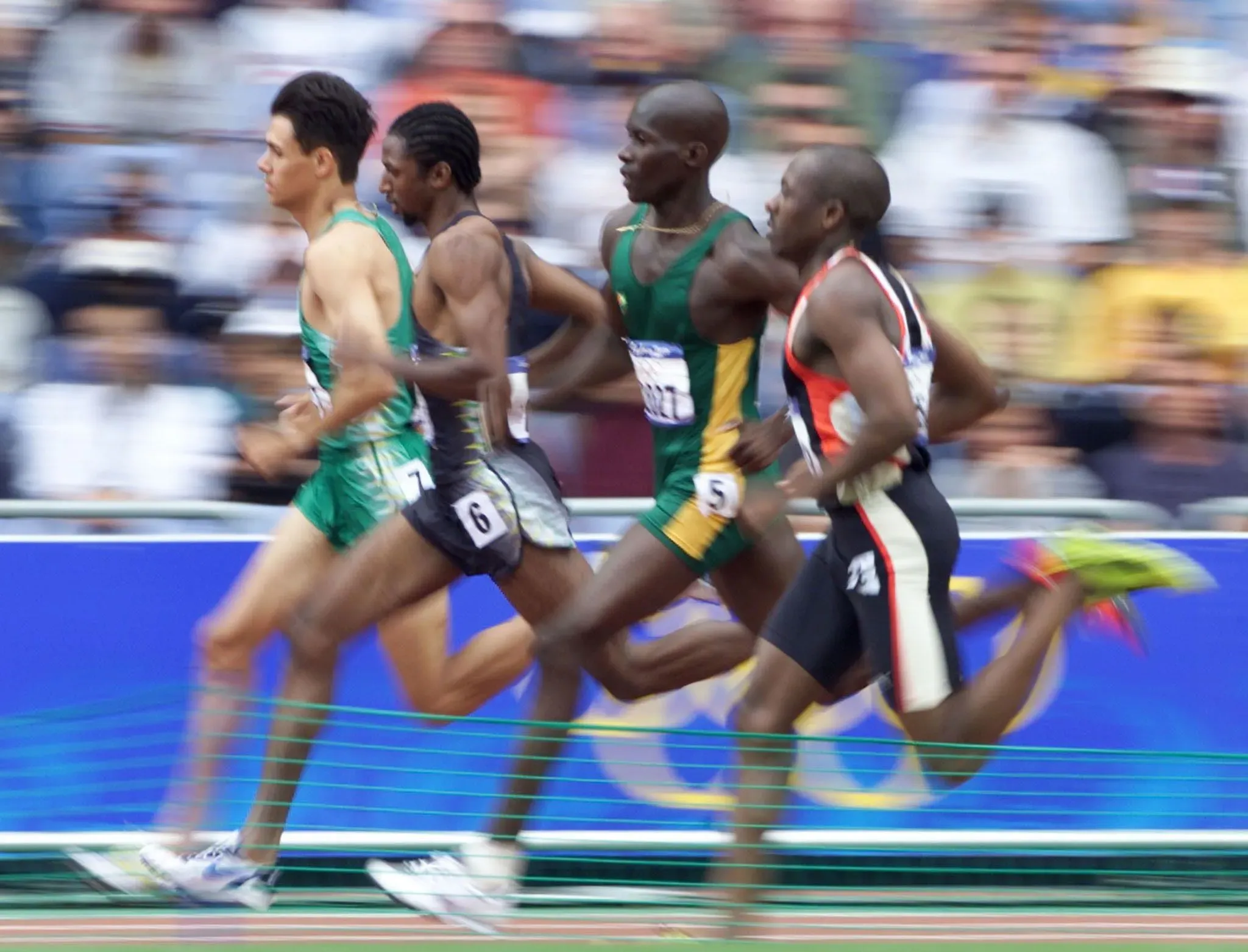 عداءون يتسابقون في سباق 100 متر خلال دورة الألعاب الأولمبية، مع تركيز على المنافسة بين المشاركين.