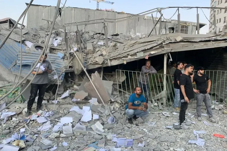 دمار كبير في مبنى بعد القصف الإسرائيلي في طهران، مع تجمع عدد من الأشخاص وسط الأنقاض، مما يعكس تصاعد التوترات الإقليمية.