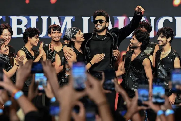 احتفال حيوي لإطلاق ألبوم فيلم "دوراندهار" في نيودلهي، حيث يظهر الممثل رانفير سينغ وسط فريقه، مع تفاعل الجماهير.