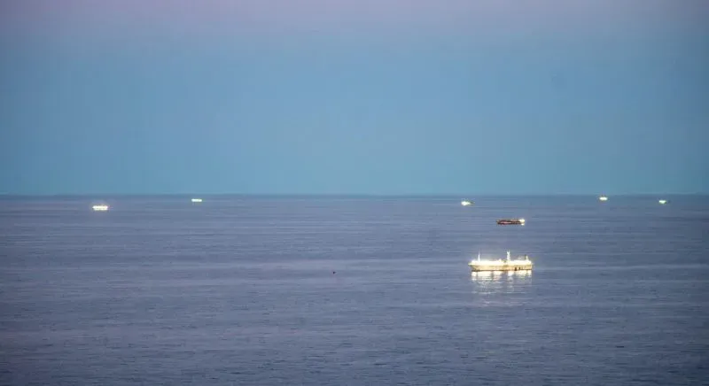 سفن صيد مضاءة في البحر قبالة سواحل الأرجنتين، تظهر نشاط الصيد غير القانوني في المنطقة الاقتصادية الخالصة.