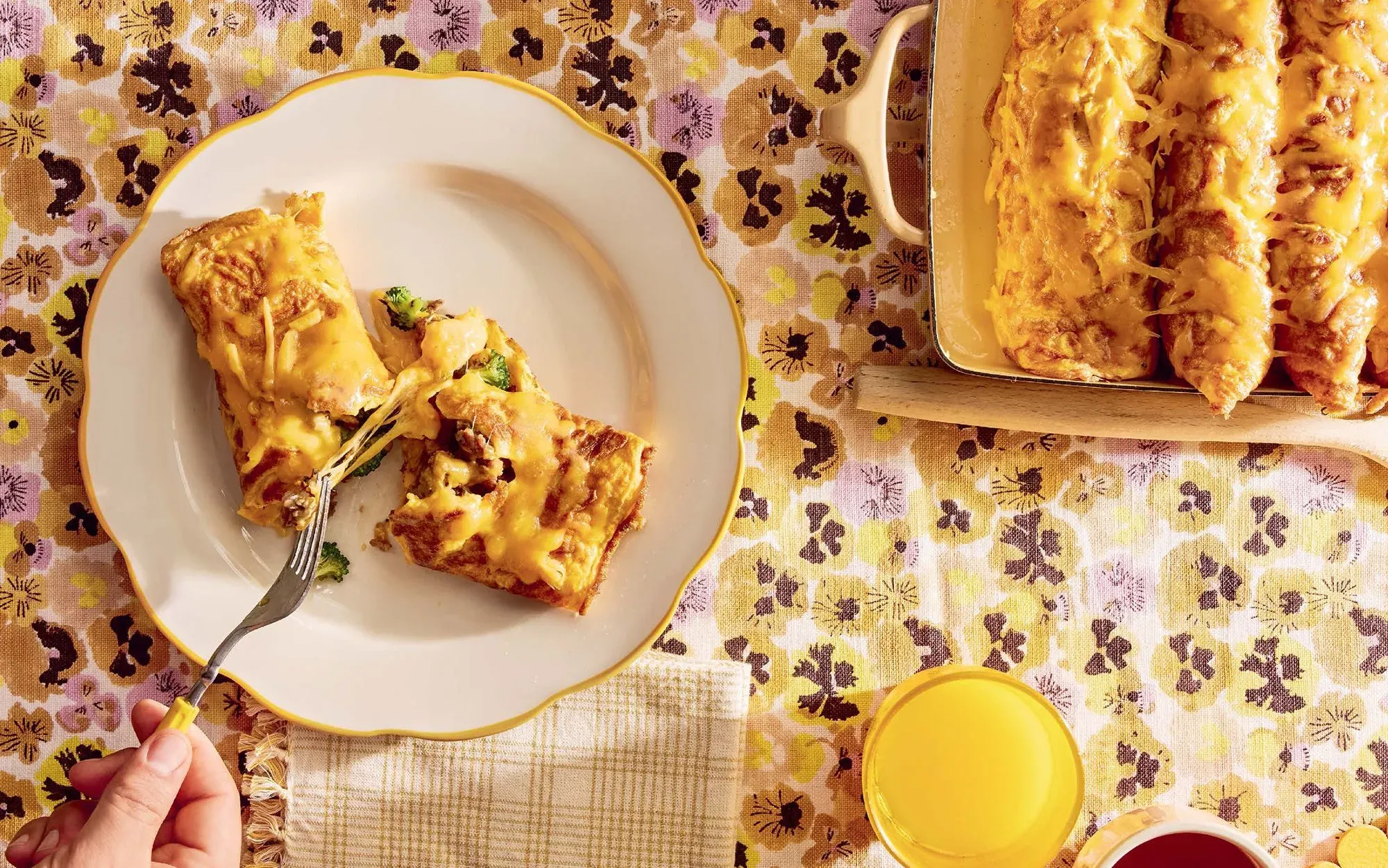 طبق عجة البيض المخفوق مع الجبن والبروكلي، يُقدم على طبق مزخرف مع مشروبات، يعكس أجواء حفلة فطور مميزة.