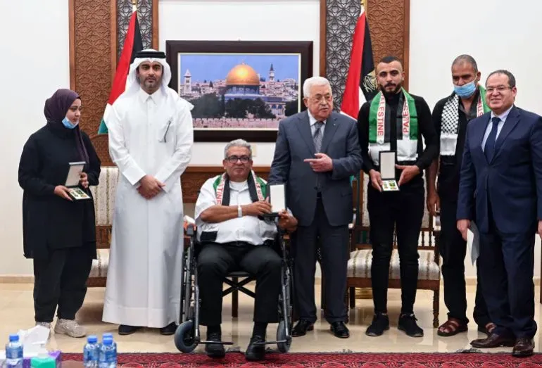 تجمع عدد من الأشخاص في احتفال رسمي، حيث يتوسطهم الرئيس الفلسطيني محمود عباس، لتكريم الصحفيين الفلسطينيين.