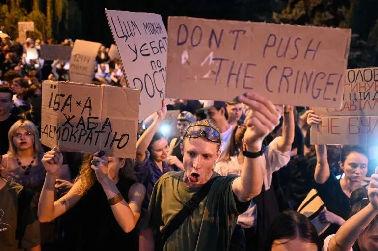 محتجون أوكرانيون يحملون لافتات تعبر عن رفضهم لمشروع قانون يهدد استقلالية هيئات مكافحة الفساد، خلال مظاهرة في كييف.