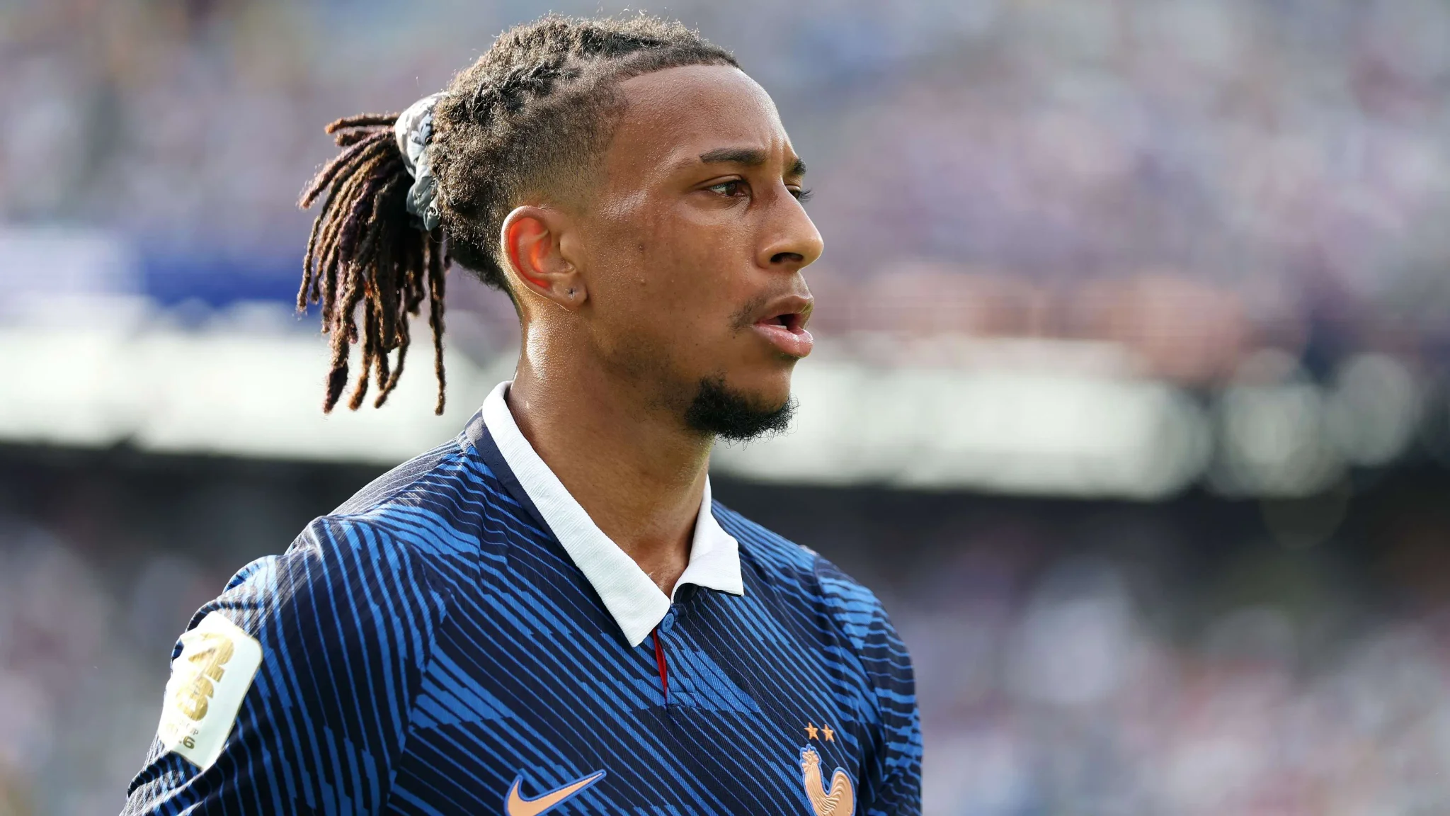 لاعب كرة القدم مايكل أوليس يرتدي قميص المنتخب الفرنسي خلال بطولة كأس العالم 2026، مع تركيز واضح وأسلوب لعب ناضج.