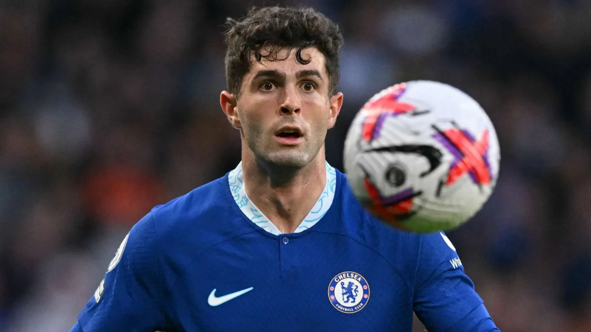كريستيان بوليسيتش لاعب تشيلسي يركز على الكرة أثناء مباراة كرة قدم، يعكس تحدياته ومسيرته بين الأندية الأوروبية الكبرى.
