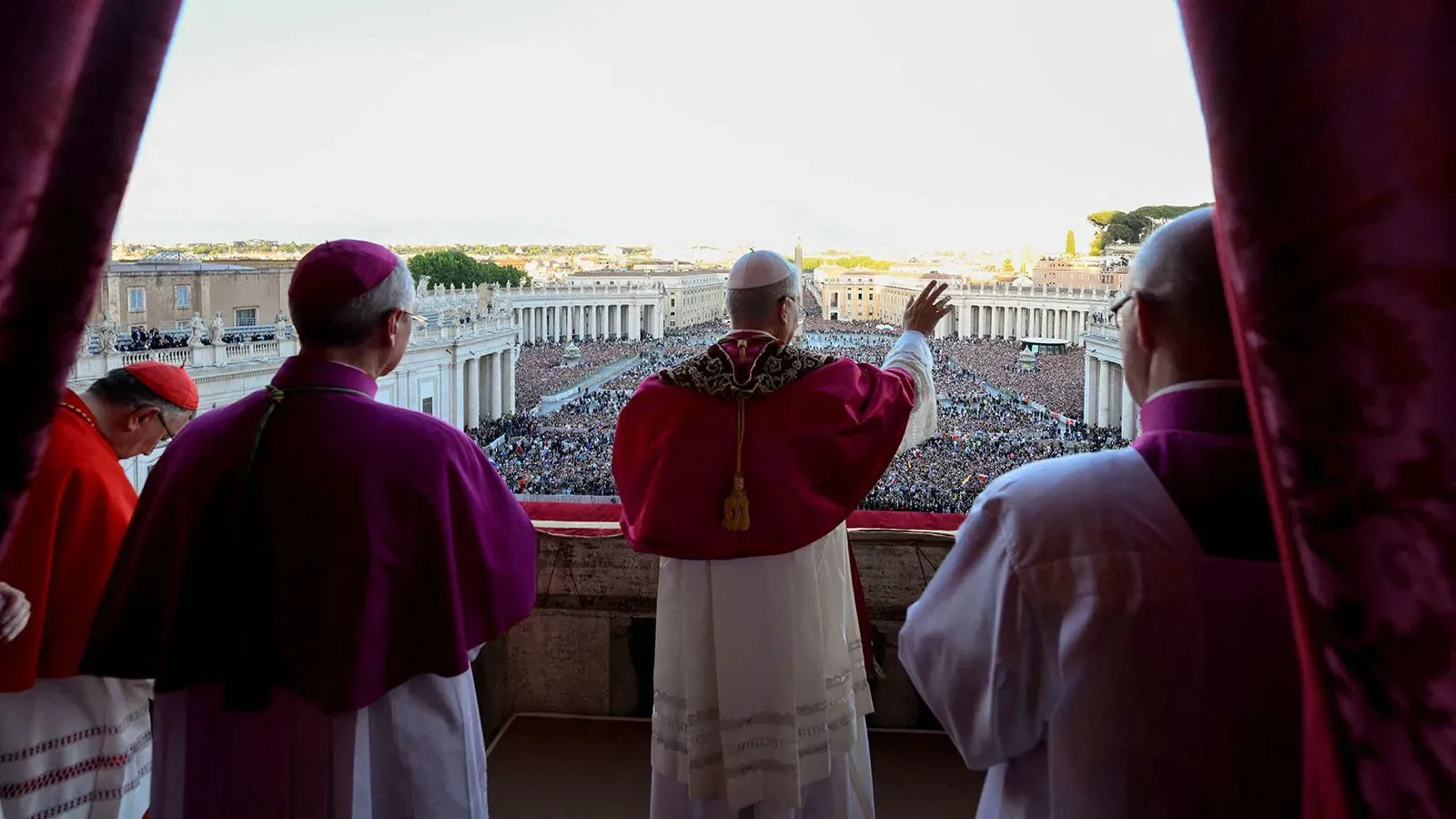 البابا الجديد يلوح للجماهير من شرفة الفاتيكان، محاطًا بكاردينالات، في لحظة تاريخية بعد انتخابه.