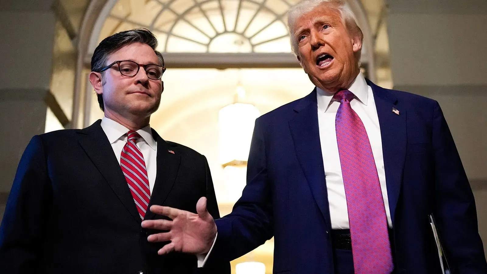 ترامب يتحدث مع مسؤول حكومي، مع خلفية مضاءة في قاعة، في سياق مناقشات حول سوق السندات والاقتصاد الأمريكي.